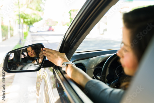 Tablou pe pânză Woman adjusting car side mirror during adult driving lesson, focusing on safety