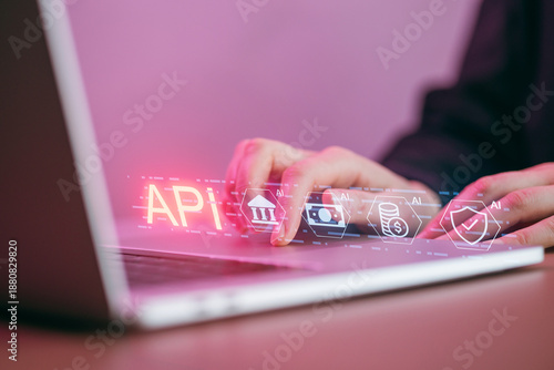 Hands work on laptop showing API interface with graphics in a workspace during afternoon hours