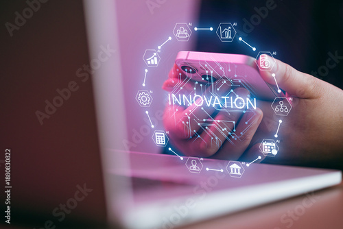 Hands holding a smartphone with innovation symbols and a laptop in the background