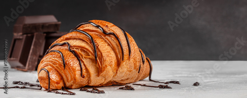 Tableau sur toile Chocolate drizzled croissant with dark chocolate on light table