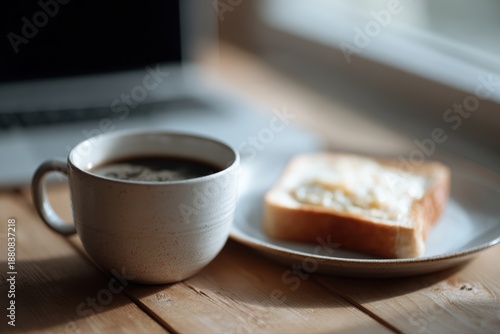 Coffee and toast beside laptop on wooden table, relaxed morning remote work setup