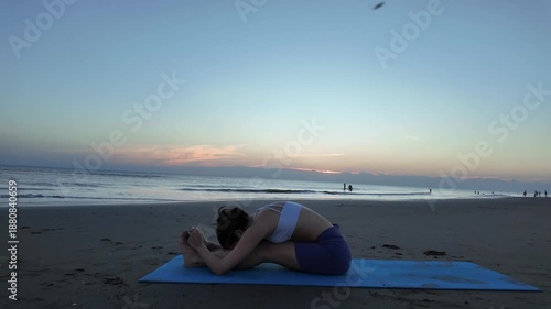 Lesbian woman doing yoga meditation on the beach at sunset
