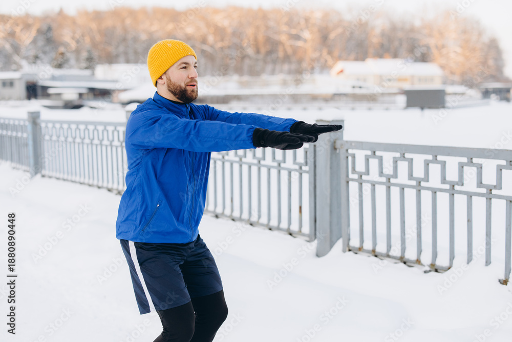 Obraz premium Man doing squats outdoors in winter, exercising for fitness, health, and well being in a snowy environment