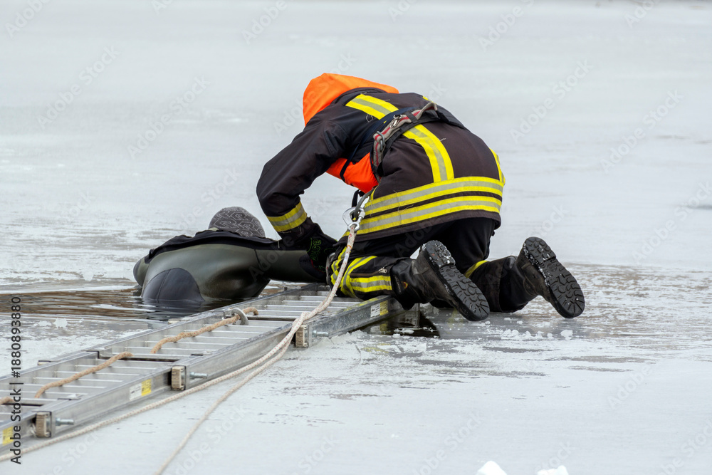 Naklejka premium Firefighter rescues person from icy water during winter emergency response operation near frozen lake