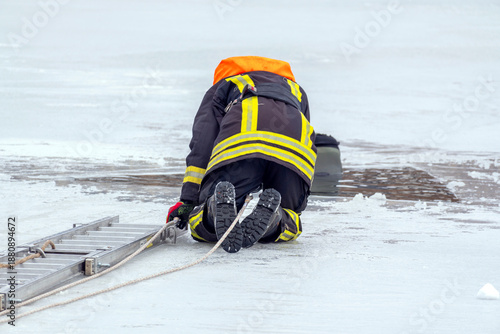 Firefighter performs rescue operation on icy water surface in winter