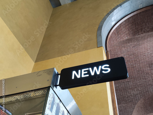 News sign illuminated in a modern building with yellow walls and curved architectural details highlighting contemporary design elements