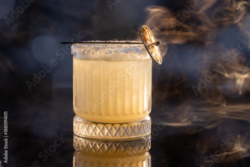 Refreshing smokey margarita with salt on the rim served on ice garnished with a grilled lime wheel.