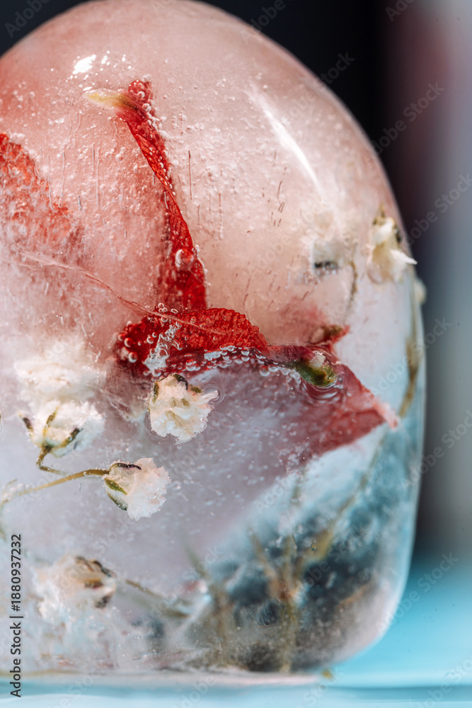 Fototapeta premium Close up of ice Easter egg with red petals and tiny flowers on blue. High quality photo