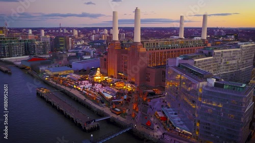 Festive Christmas lights glow around Battersea Power Station beside the Thames at twilight, with London skyline beyond; perfect for holiday travel, real estate and urban branding