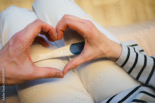 Tablou pe pânză Woman's hands creating a heart around a positive pregnancy test, representing th