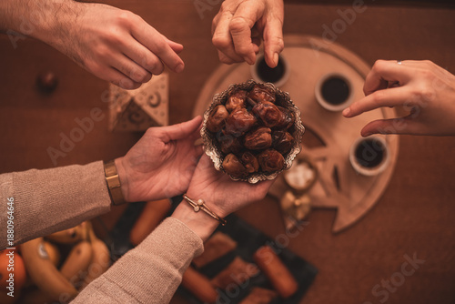 Hands Sharing Dates During Ramadan Celebration Close-Up Top View of Generational Family Members Enjoying Traditional Food Together During Iftar Meal at Home.