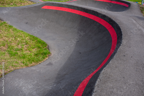Empty BMX cycle pump track with a red line on top edge as the track curves round. 