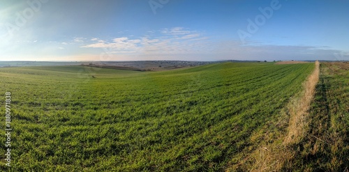 Scenic view of rolling green hills under blue sky with clouds during daytime in a rural landscape