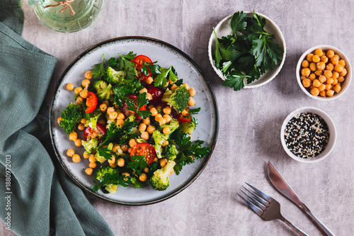 Vegetarian salad with chickpeas, tomatoes, broccoli and greens on a plate on the table top view