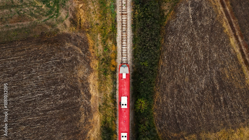 Aerial view of passenger train on railway through autumn countryside landscape, top view