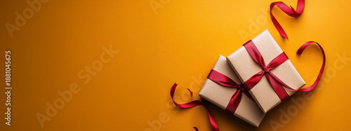 Gifts wrapped with red ribbons placed on a bright yellow surface during a celebration