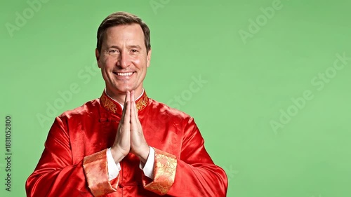 Smiling man in traditional red Chinese attire with hands clasped