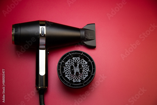 Close-up black hair dryer and hair dryer nozzle diffuser for creating curls on a pink background with space for text. The concept of long-term hair styling, hairstyles, curls and hair care. High