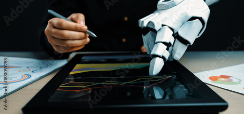 Fotografie A captivating scene of a robotic arm and a human hand working together on a touchscreen device, demonstrating advanced technology in data analysis and visualization