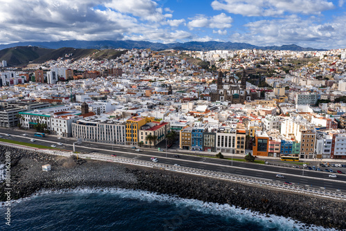 Obraz na płótnie Aerial coastal skyline of Las Palmas de Gran Canaria shows rocky shore, seafront road, low rise buildings, and twin towered Cathedral of Santa Ana under soft light and clouds