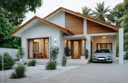 Modern tropical house exterior with wooden roof details white walls landscaped garden and driveway at sunset