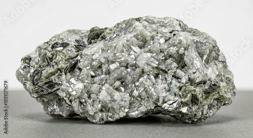 A collectible geological specimen of crystalline sugar magnesite with a typical grained white texture in silvery-gray talc schist with long, acicular crystals of green actinolite.