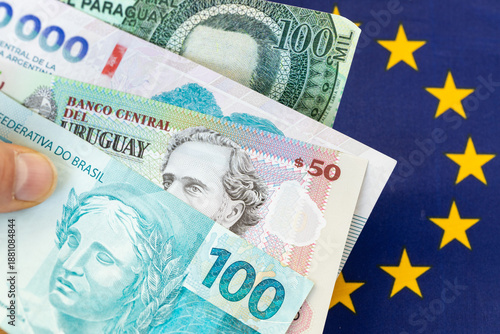 Mercosur trade agreement with the European Union. Business concept. Banknotes of Brazil, Argentina, Paraguay, and Uruguay against the backdrop of the European Union flag © Rochu_2008