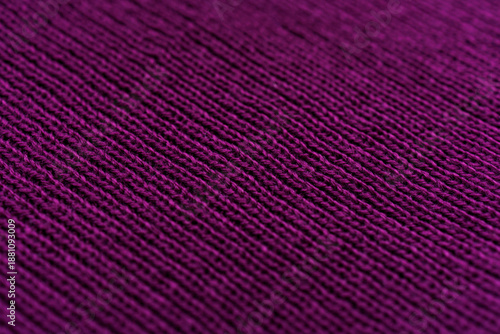 Angled view of purple knitted textile showing fine ribbed structure captured as abstract warm fabric surface