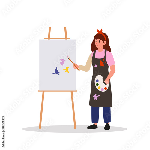 Artist painting picture on easel. Young woman in ponytail holds paintbrush and paint palette with various colors. She is smiling.