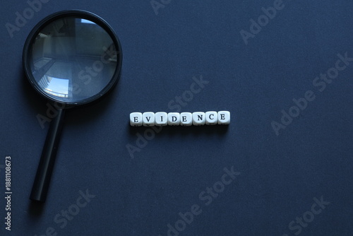 Foto Letter tiles spelling evidence beside magnifying glass on dark background, representing proof, investigation, justice, research, and verification