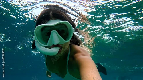 Woman swimming underwater and taking a selfie while snorkeling