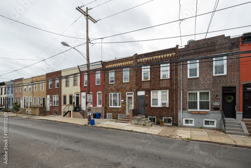 Street level view of a road and a long line of rowhouses without cars in a South Philadelphia neighborhood, Pennsylvania, USA