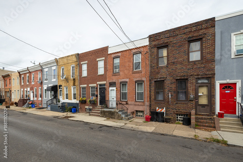 Street level view of a road and a long line of rowhouses without cars in a South Philadelphia neighborhood, Pennsylvania, USA