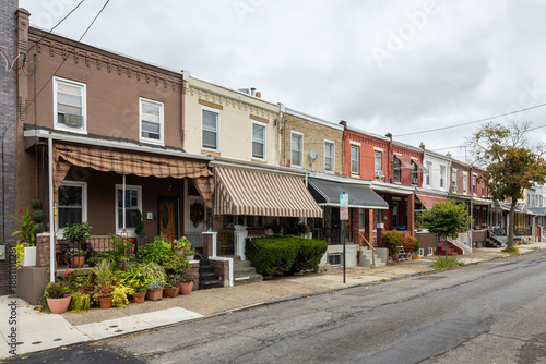 Street level view of a road and a long line of rowhouses without cars in a South Philadelphia neighborhood, Pennsylvania, USA