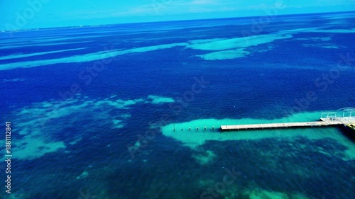 Wallpaper Mural Cinematic 4K aerial drone shot flying forward from an empty wooden pier out into the vast, turquoise Caribbean Sea in Cancun, Mexico, under a clear, bright blue sky Torontodigital.ca