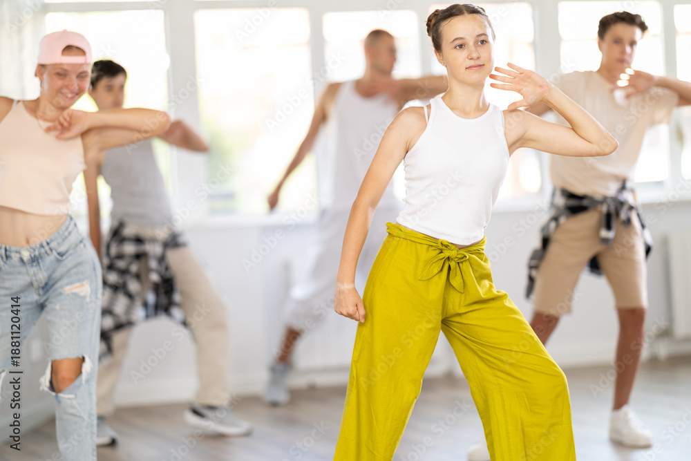 Fototapeta premium Teen girl dancing jazz funk in group of teenagers in dance studio