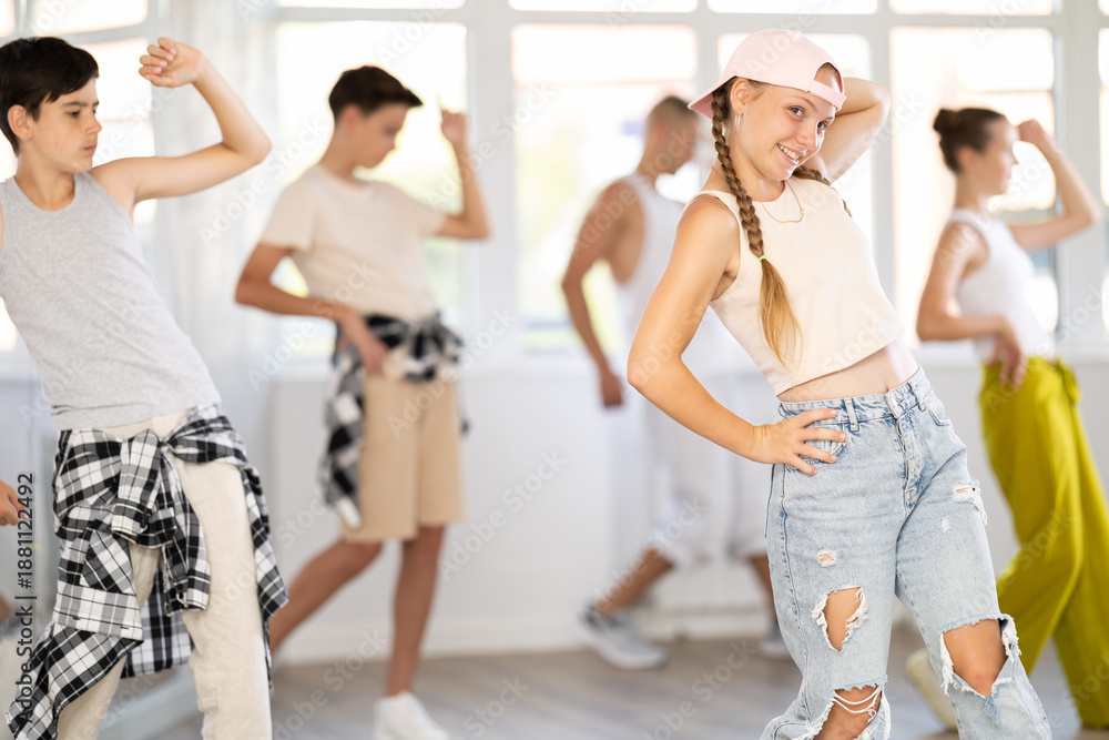 Fototapeta premium Dynamic teen girl training hip hop slides in dancehall during workout session in group