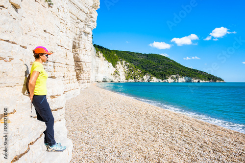 Wallpaper Mural Female traveler relaxing on a quiet pebble Vignanotica beach beneath the white cliffs and turquoise sea of the Gargano Coast, Apulia, Italy Torontodigital.ca