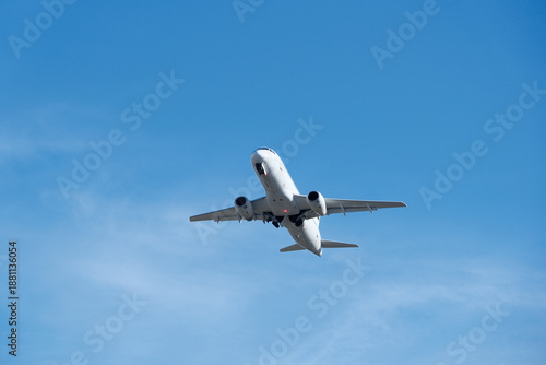 White commercial airplane climbing in clear blue sky after takeoff. White plane climbing after takeoff against the blue sky