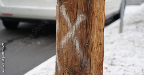 Bild auf Leinwand Close up of a wooden utility pole marked with a white spray-painted X for mainte