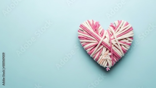 A heart-shaped object made of twisted paper in pink and white hues on a blue background