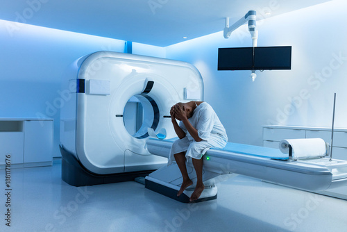 CT scanner gantry dominating left side and motorized exam table extending right with blue LEDs