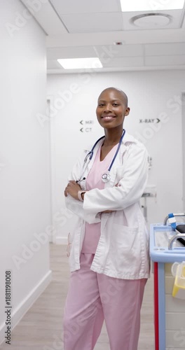 Vertical video: Woman clinician in coat standing arms crossed in corridor, camera moving reassuring