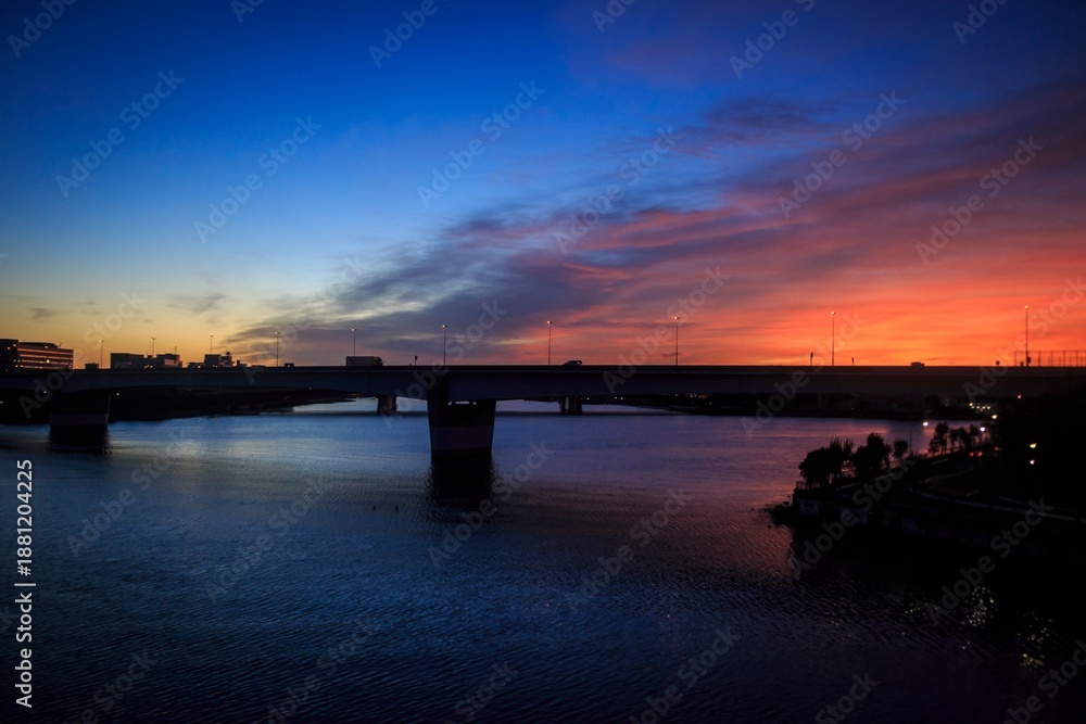Fototapeta premium Dramatic Sunset Glow Over a Silhouetted City Bridge