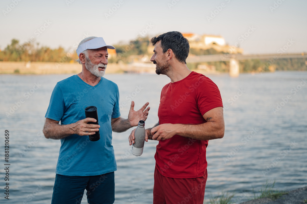Obraz premium Senior and young man talking after exercising by the river