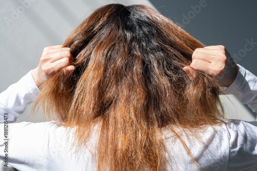 фотографія Rear view of young woman while touching her messy and frizzy hair