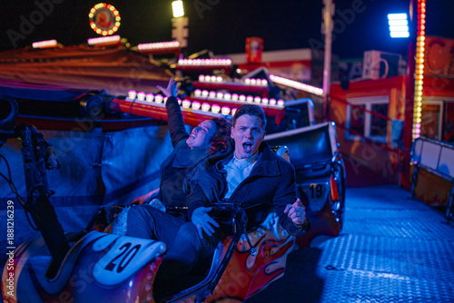 Bilde på lerret Young couple enjoying thrilling fairground ride at night