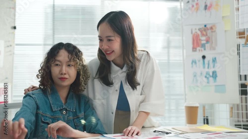 Two professional Asian graphic designers collaborate intensely in their modern creative studio, brainstorming and discussing innovative concepts for a new corporate identity branding project, review