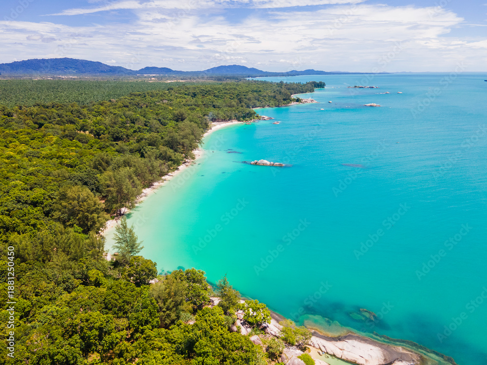 Fototapeta premium Aerial view of Membalong Beach in Belitung, Indonesia. A pristine tropical coastline featuring turquoise water, lush green forest, and giant granite rock formations.