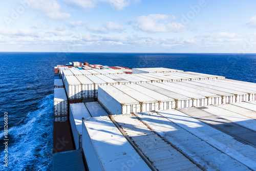 Foto View from the bridge towards the bow of a container vessel with white reefer containers on deck, sailing through calm ocean waters